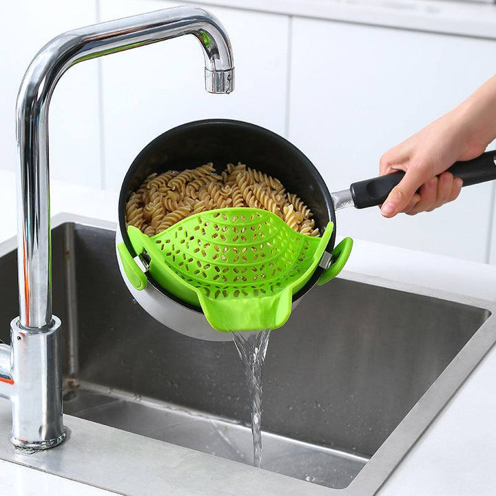 Silicone pot side drain stopper in use, straining pasta over sink.
