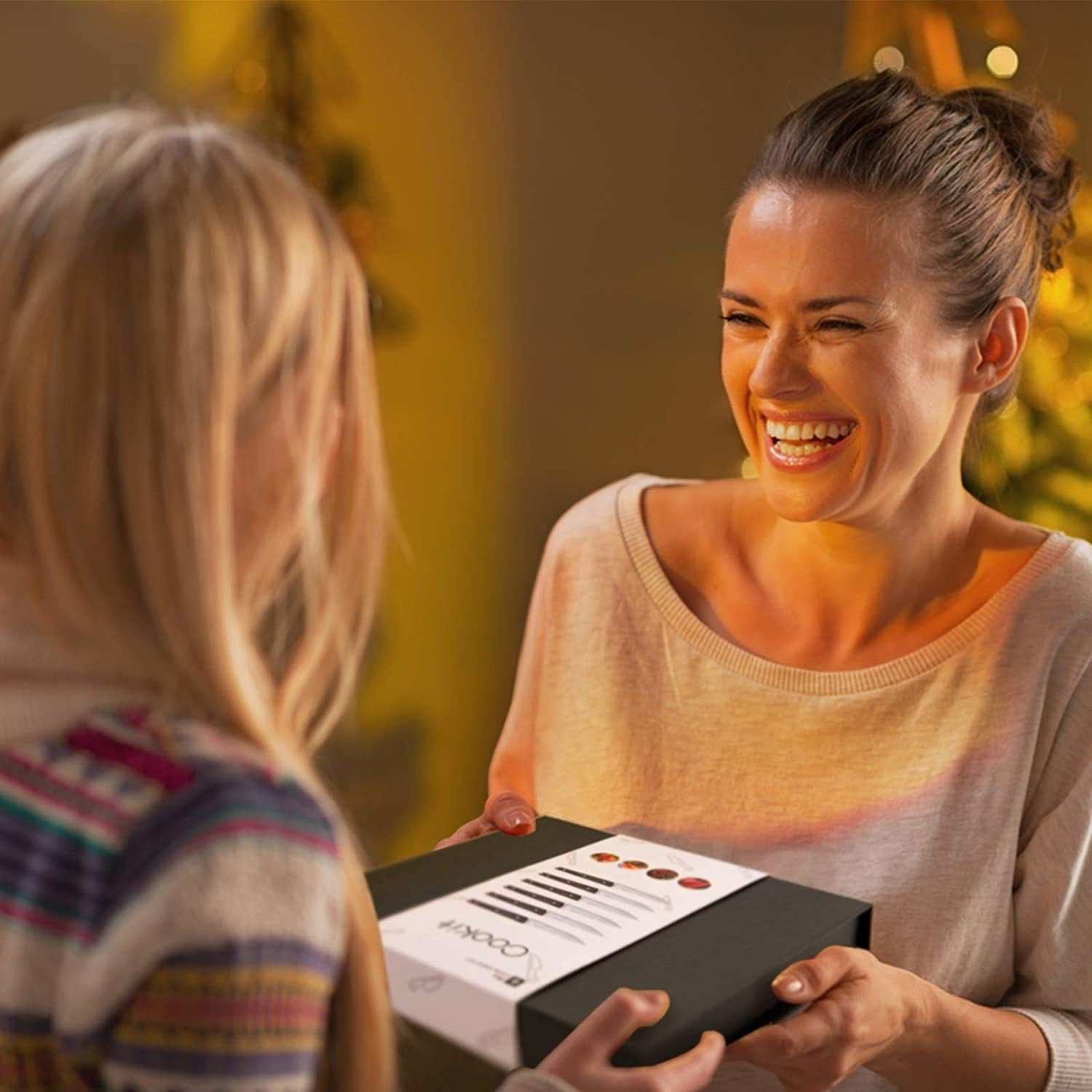 Woman gifting a box of high-quality serrated steak knives with wooden handles, suitable for home or restaurant use.