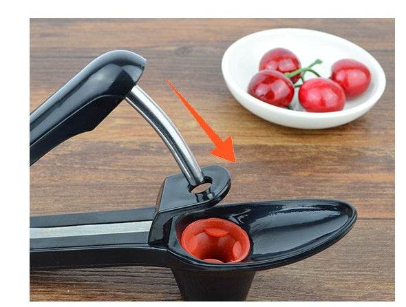 Cherry red date cherry kernel remover tool in black ABS material on wooden surface.