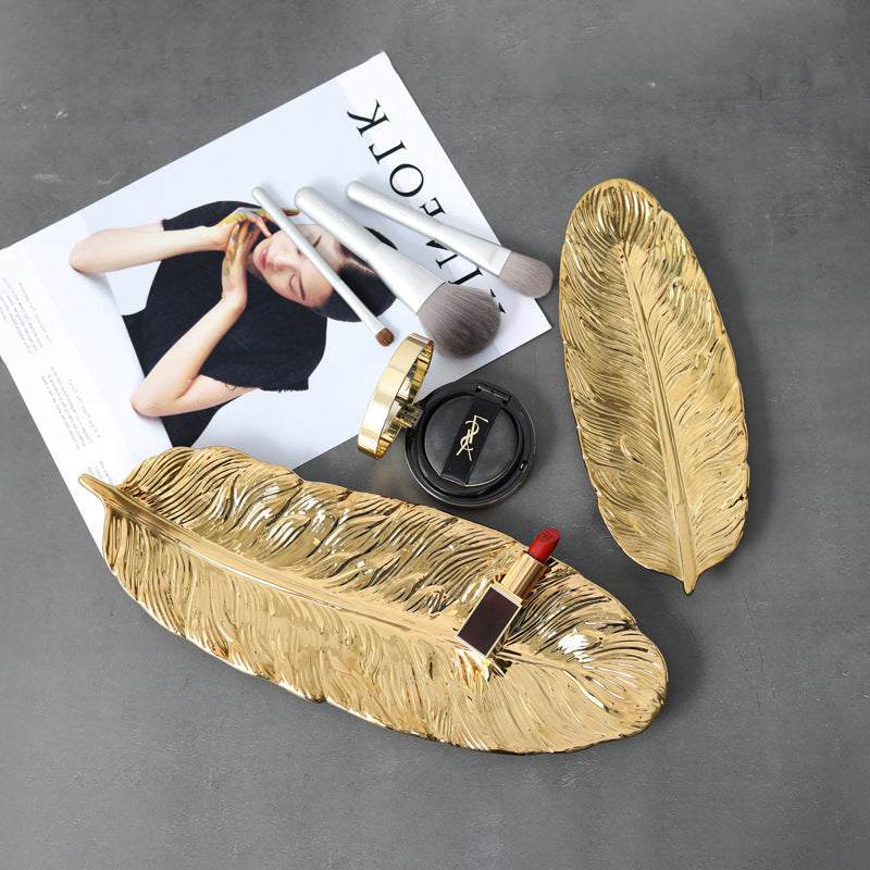 Golden ceramic leaf-shaped storage trays with decorative items.