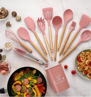 Silicone kitchenware set with wooden handles, includes various utensils, displayed on a kitchen counter.