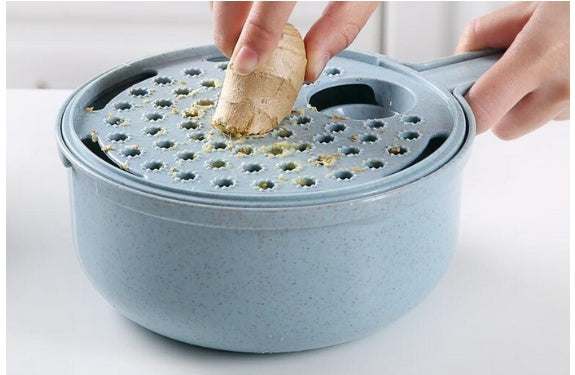 8 In 1 Mandoline Slicer grating ginger into a blue strainer bowl.