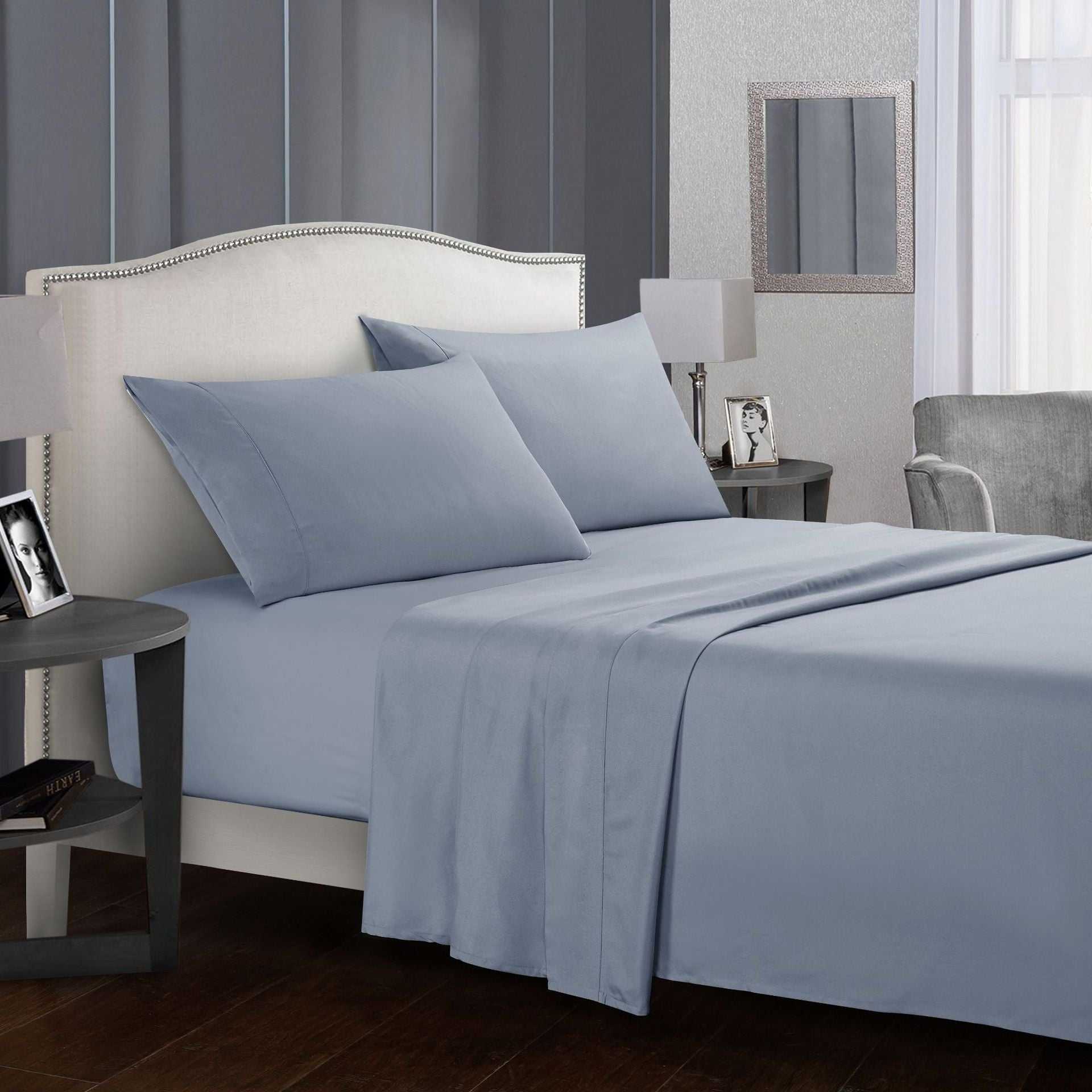 Four-piece bed sheet set with pillowcases in elegant bedroom setting.