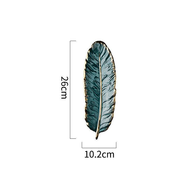 Green ceramic leaf-shaped storage tray with golden rim and smooth glaze.