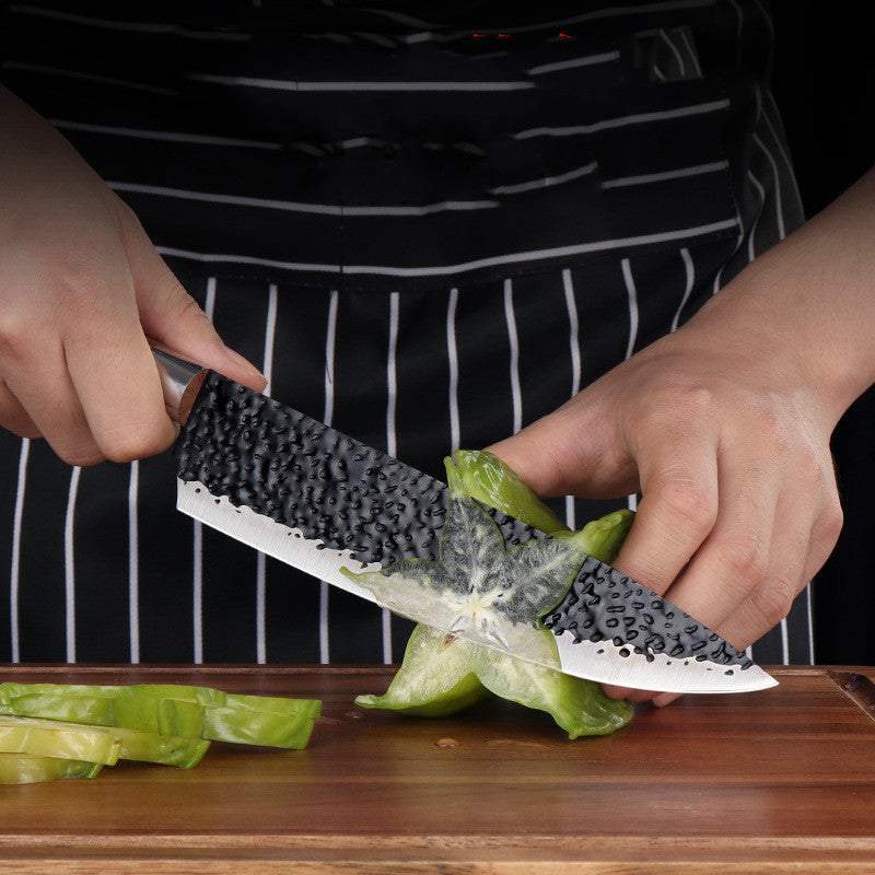 Stainless steel slicing knife cutting vegetables on a wooden board.