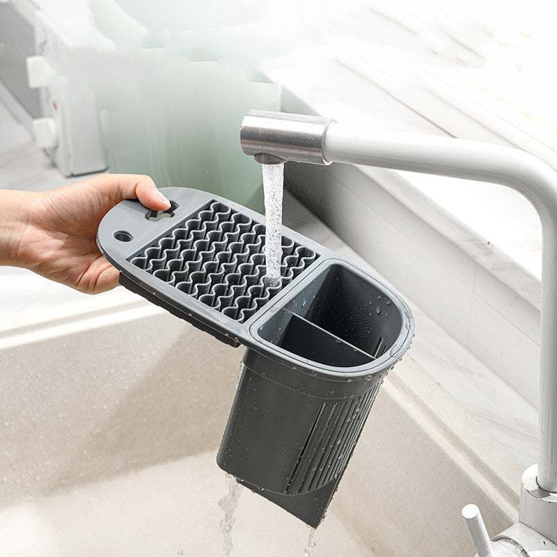 Cutlery rack draining water under faucet in kitchen sink.