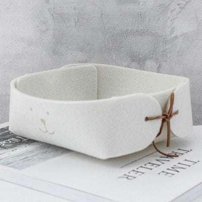 Mini wool felt storage basket with smiley face design, in beige color, suitable for jewelry and desktop organization.