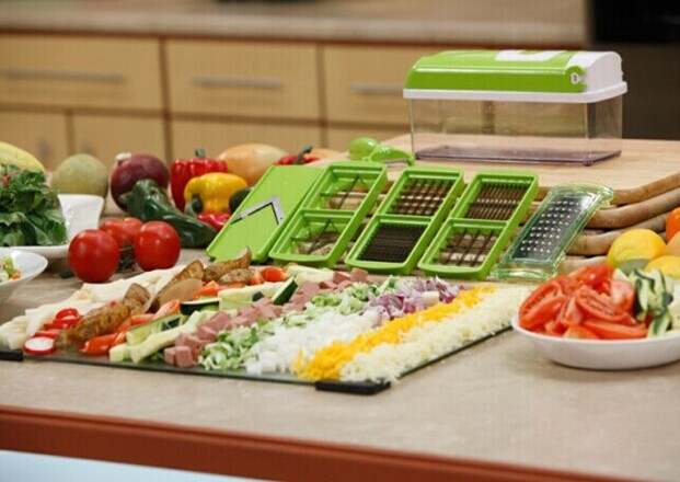 Multifunctional vegetable chopper in kitchen with assorted sliced vegetables. 