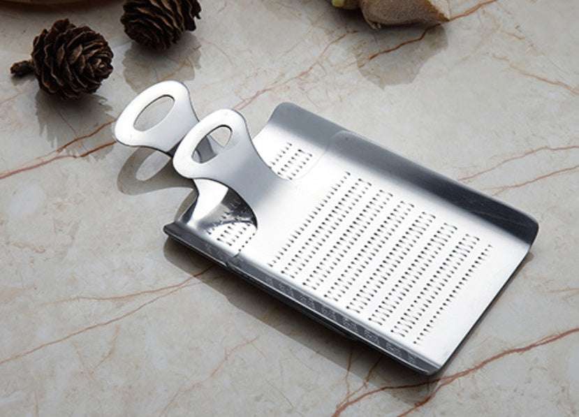 Stainless steel garlic press with ergonomic handle on marble surface.