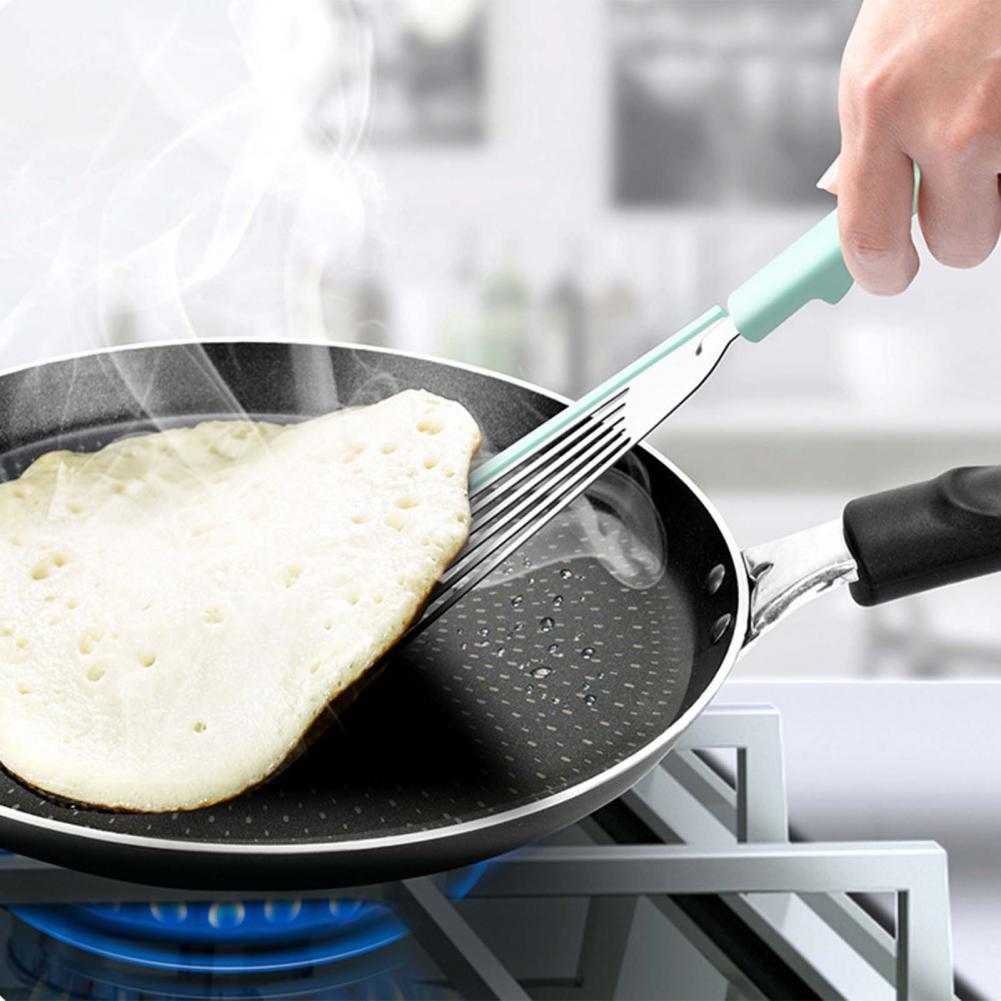 Nonstick fish spatula flipping a pancake in a nonstick frying pan.