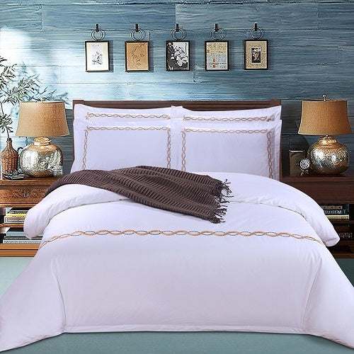 Four-piece cotton bedding set displayed on bed with decorative pillows and throw blanket.