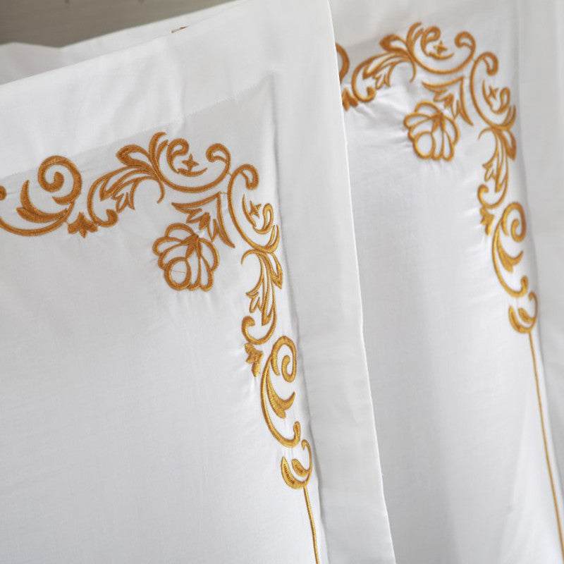 Elegant four-piece cotton bedding set with intricate gold embroidery design.