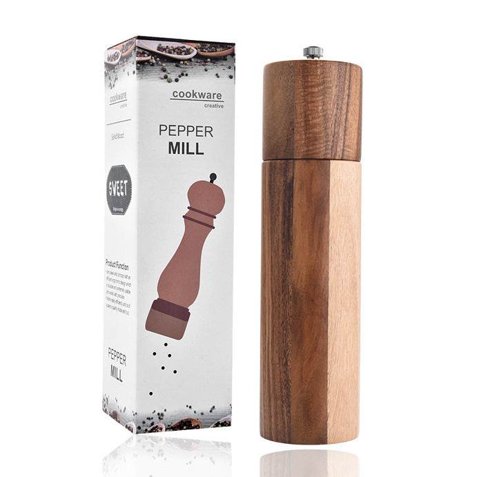 Cylindrical acacia wood pepper grinder with ceramic core next to packaging box.