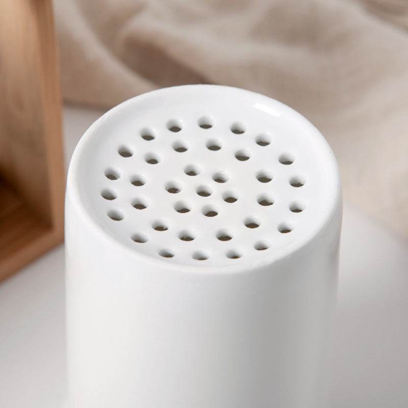 Nordic household ceramic chopstick holder with perforated design and bamboo frame.