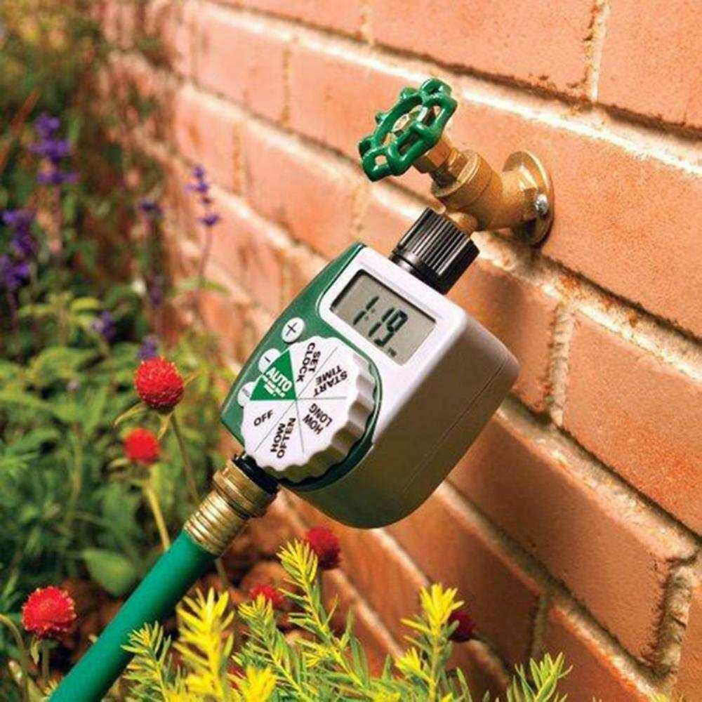 Garden irrigation controller attached to a brick wall with LCD display and dial settings.