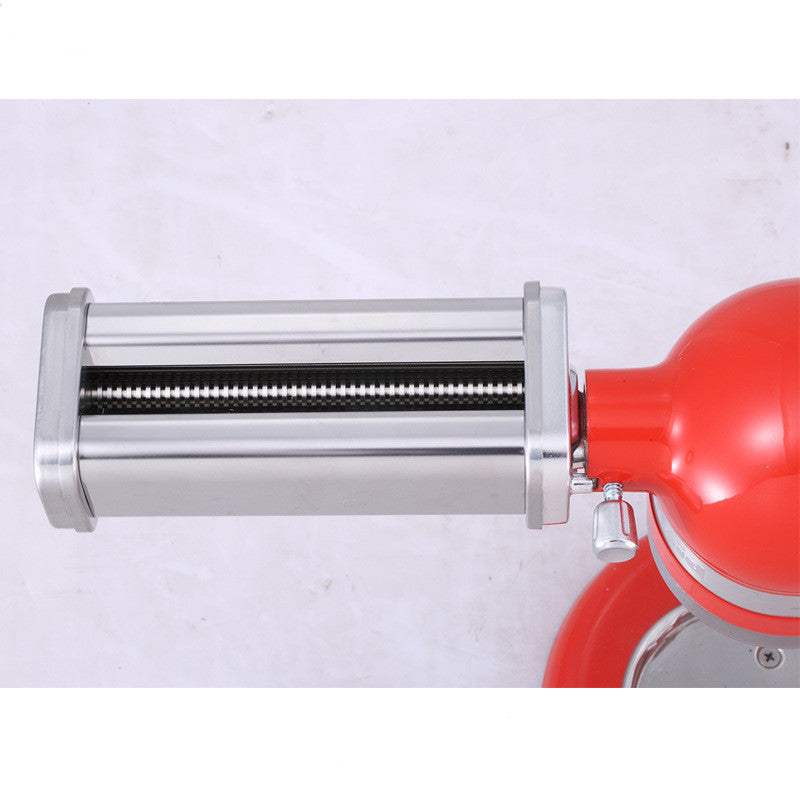 Stainless steel pasta machine attachment on red kitchen appliance.
