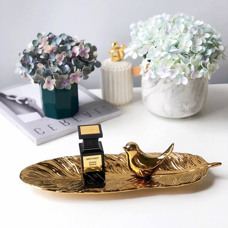 Green ceramic leaf storage tray with smooth glaze finish, used for home decoration.