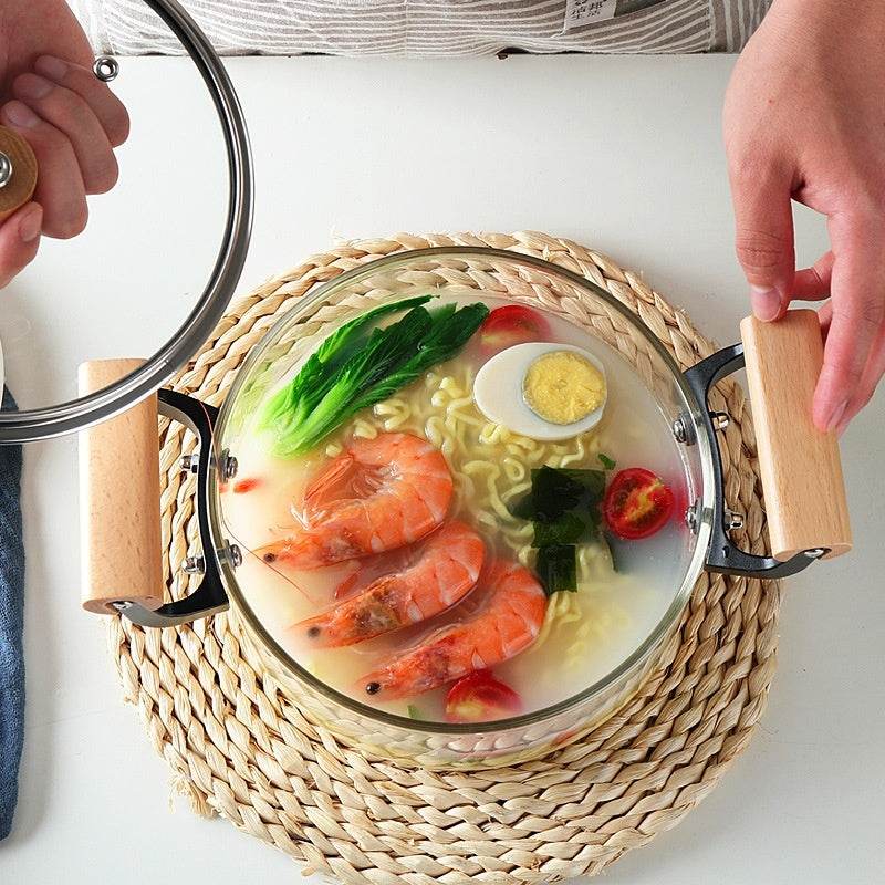 Borosilicate Visions Cookware Pot with wooden handles containing noodle soup and vegetables.