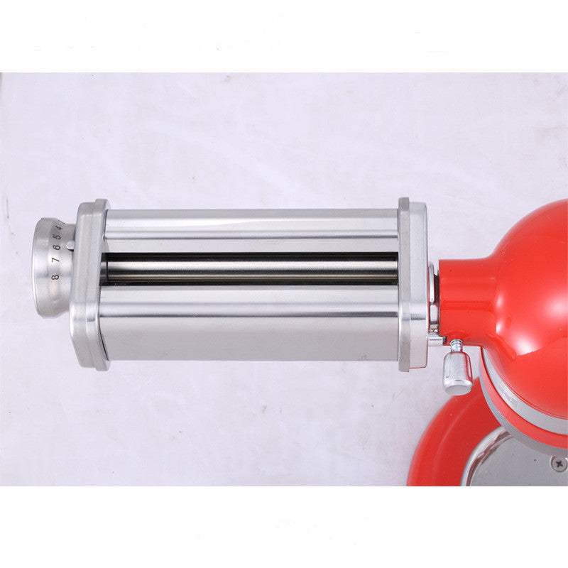 Stainless steel pasta machine accessory attached to a red kitchen appliance.