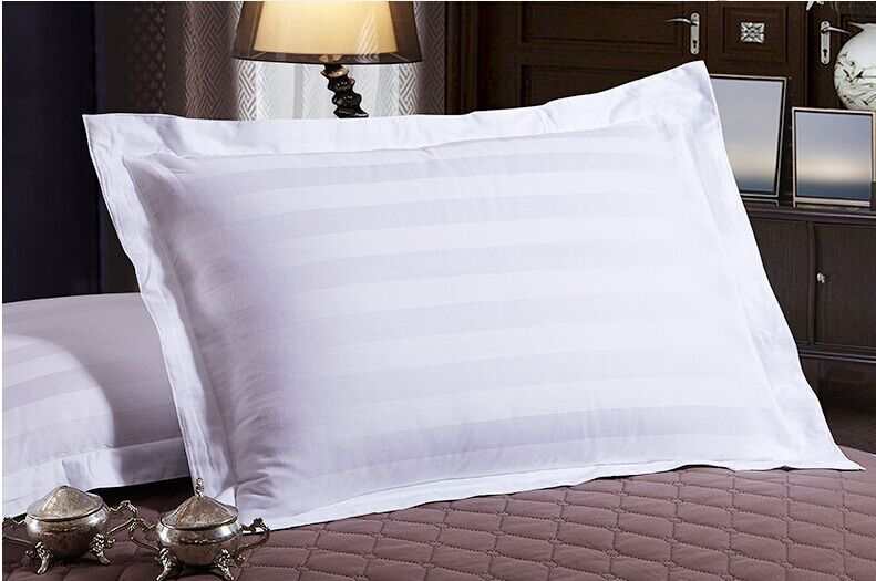 Four-piece hotel bedding set with white pillowcases on bed.