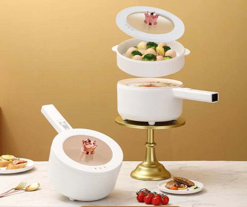 Multifunctional electric cooker with non-stick pot, steaming vegetables on a table.