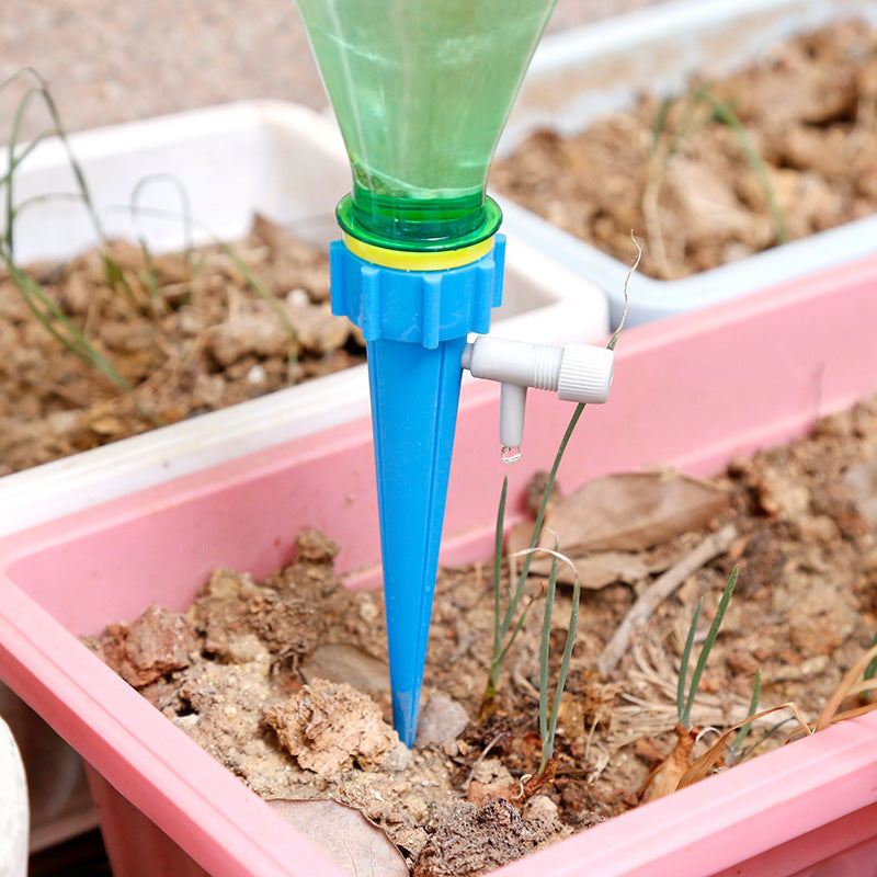 Automatic plant watering drip spike system in use with plastic bottles for efficient irrigation.
