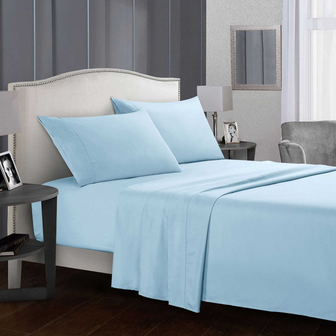 Light blue four-piece bed sheet set on a bed with pillows.