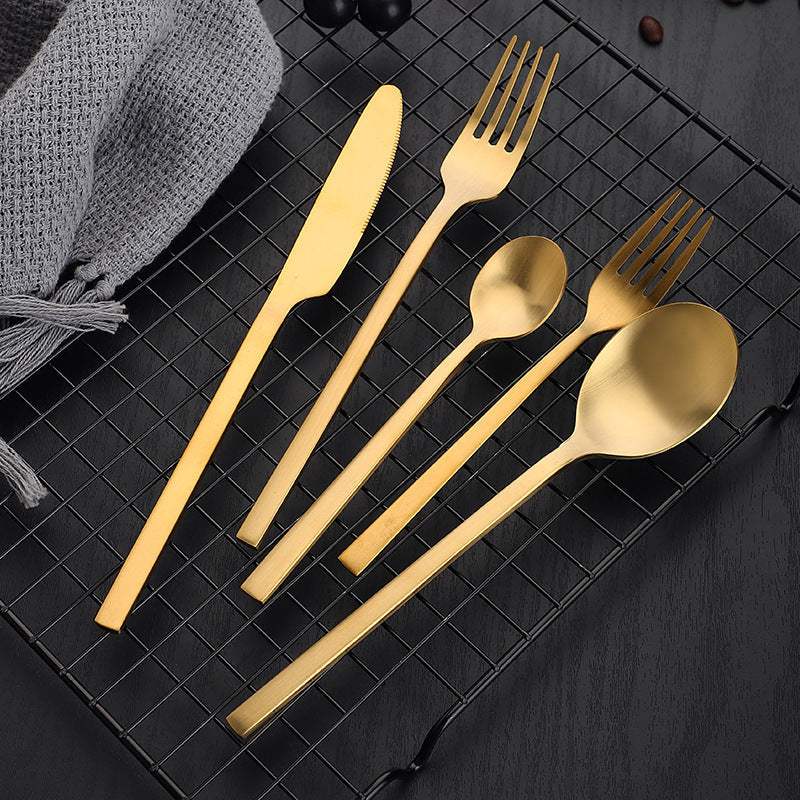 Gold matte stainless steel cutlery set on a black grid background.