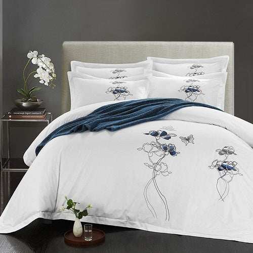 Four-piece cotton bedding set with floral design on a bed.