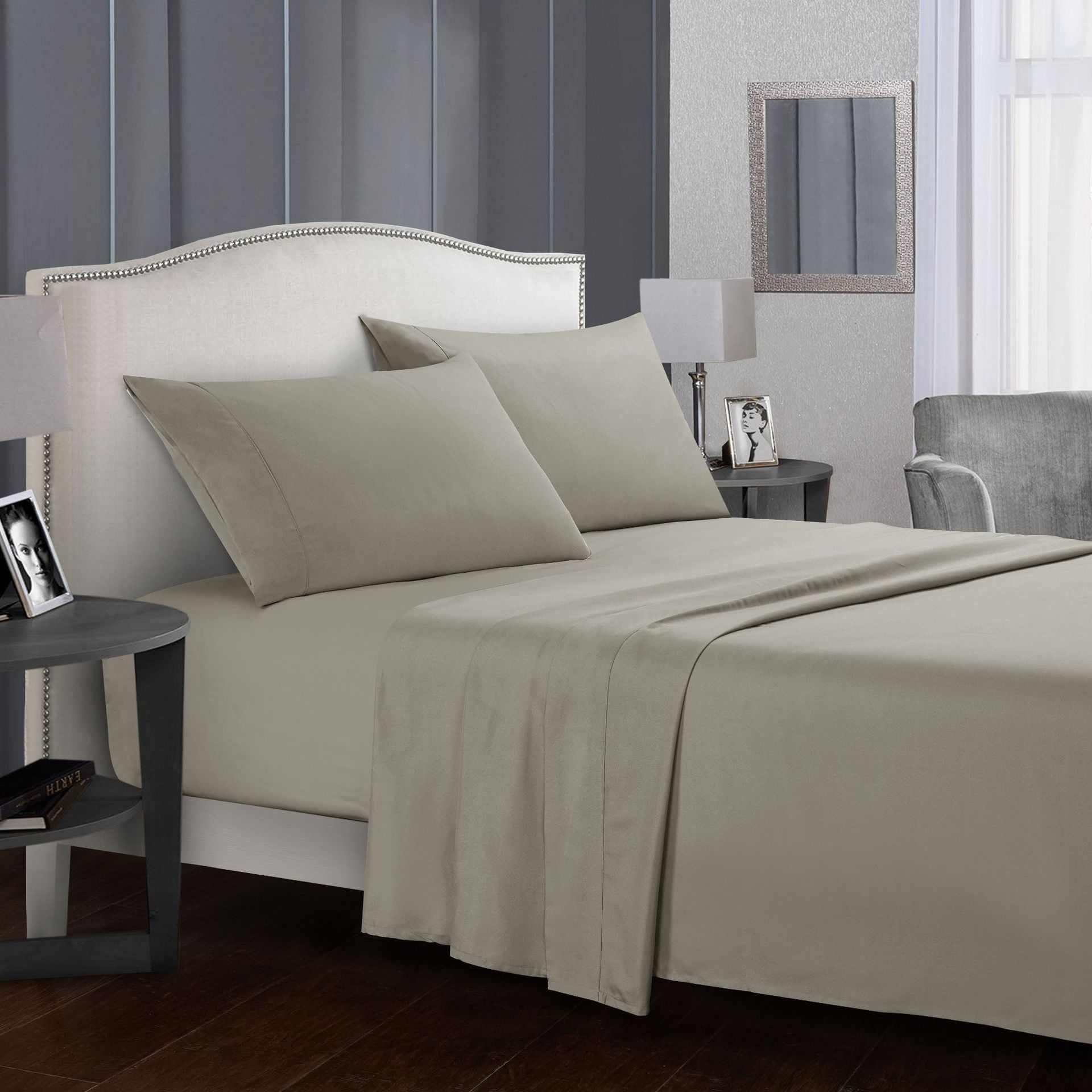 Four-piece bed sheet set on a neatly arranged bed with pillows in a modern bedroom setting.