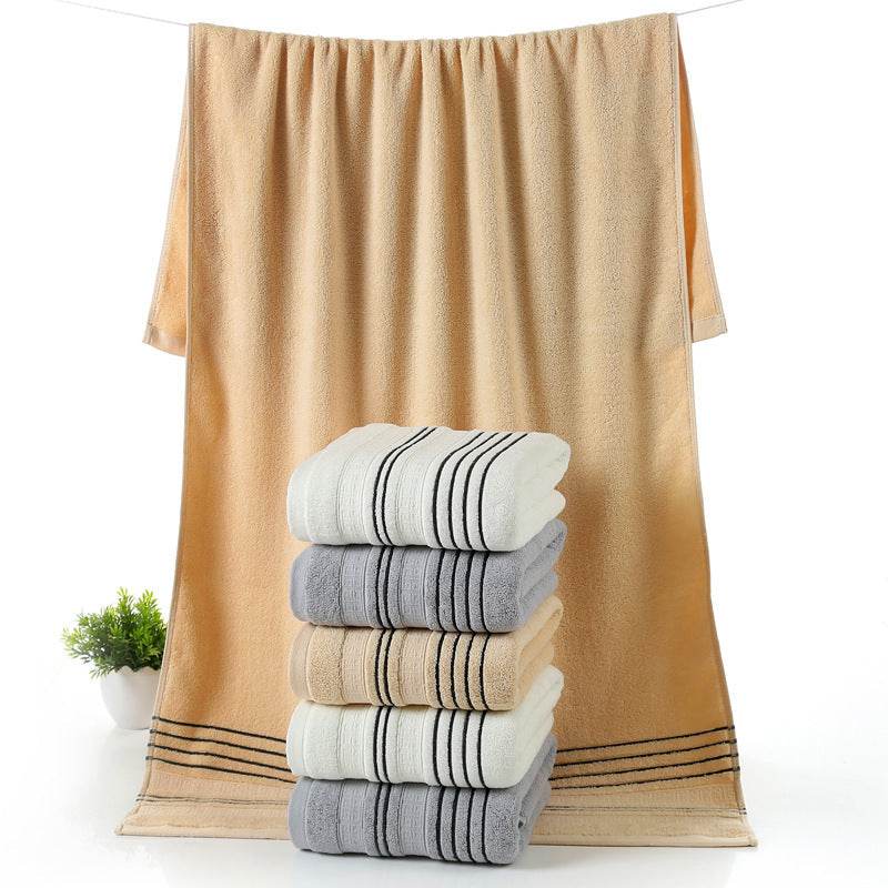 Household pure cotton towels in various colors stacked and one hanging, showcasing soft, skin-friendly fabric.
