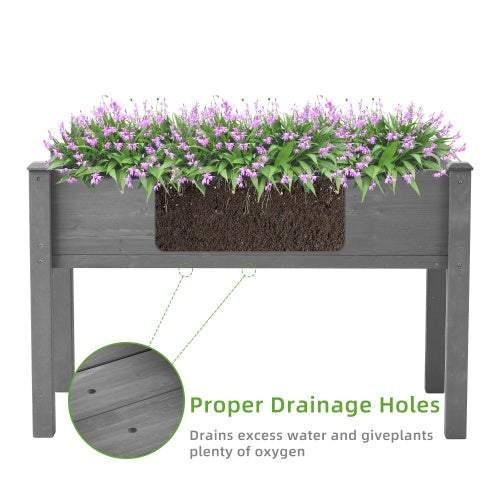 Elevated garden bed with legs, grey wooden planter filled with purple flowers, featuring drainage holes for outdoor plants.