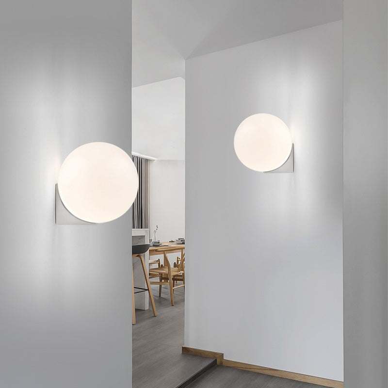 Nordic Minimalist Wall Lamp with glass shade on a white wall, featuring sleek design in a modern interior setting.