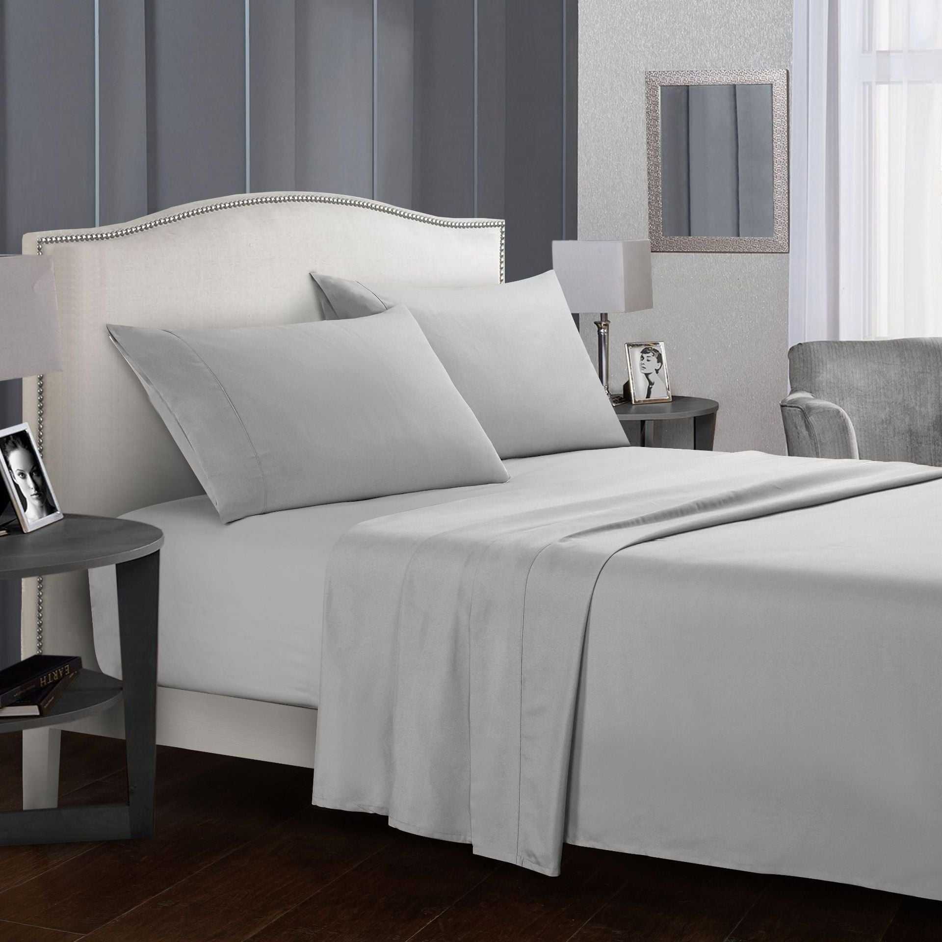 Four-piece grey bed sheet set displayed on a bed with pillows.