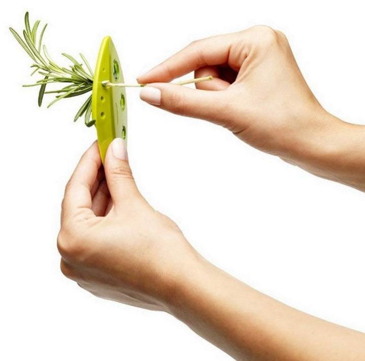 Herb stripping tool in use with fresh rosemary for easy leaf removal.