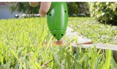 Cordless lawn trimmer in use on grass.