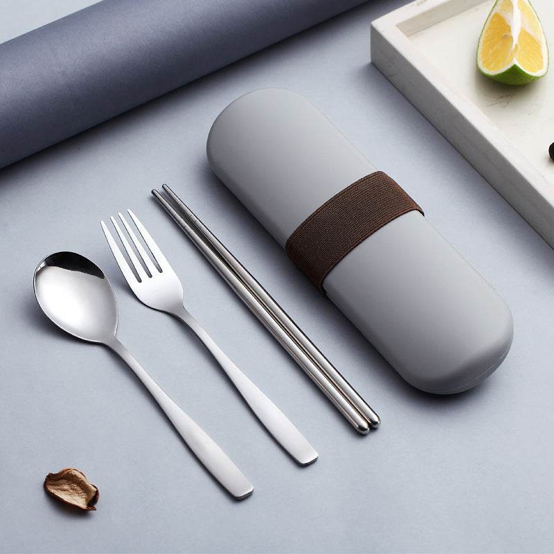 Stainless steel portable cutlery set with case, including spoon, fork, and chopsticks on a table.