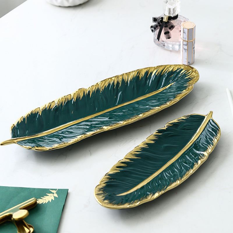 Green ceramic leaf storage tray with golden accents and smooth glaze finish.