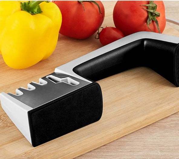 Stainless steel fast knife sharpener on a wooden cutting board with vegetables.