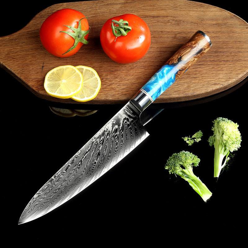 Modern stainless steel kitchen knife with etched blade and colorful handle on a wooden board with tomatoes and lemon slices.