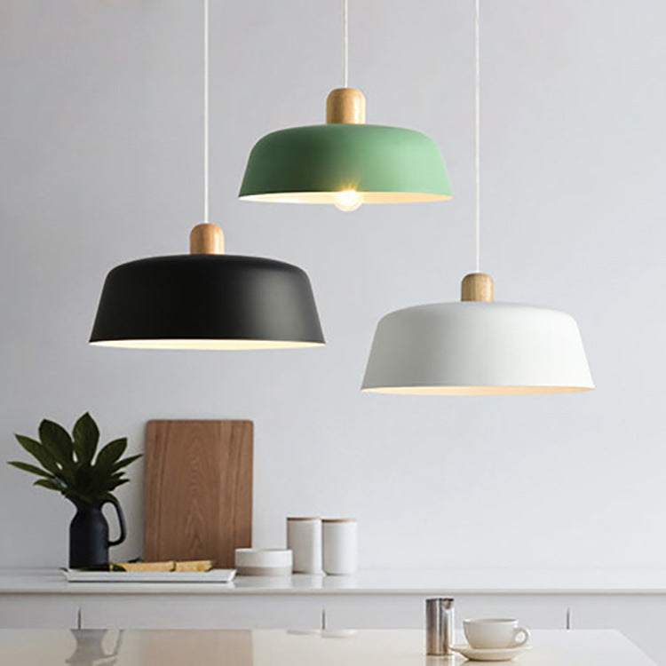 Nordic wood pendant lighting fixture in black, green, and white tones hanging in a modern dining space.