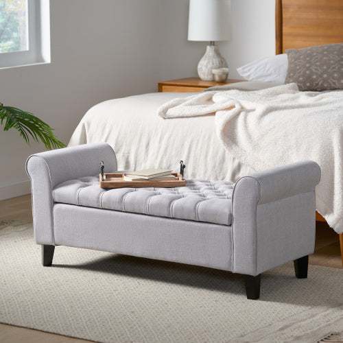Light grey fabric Hayes Armed Storage Bench with button tufting and rolled arms in a bedroom setting.