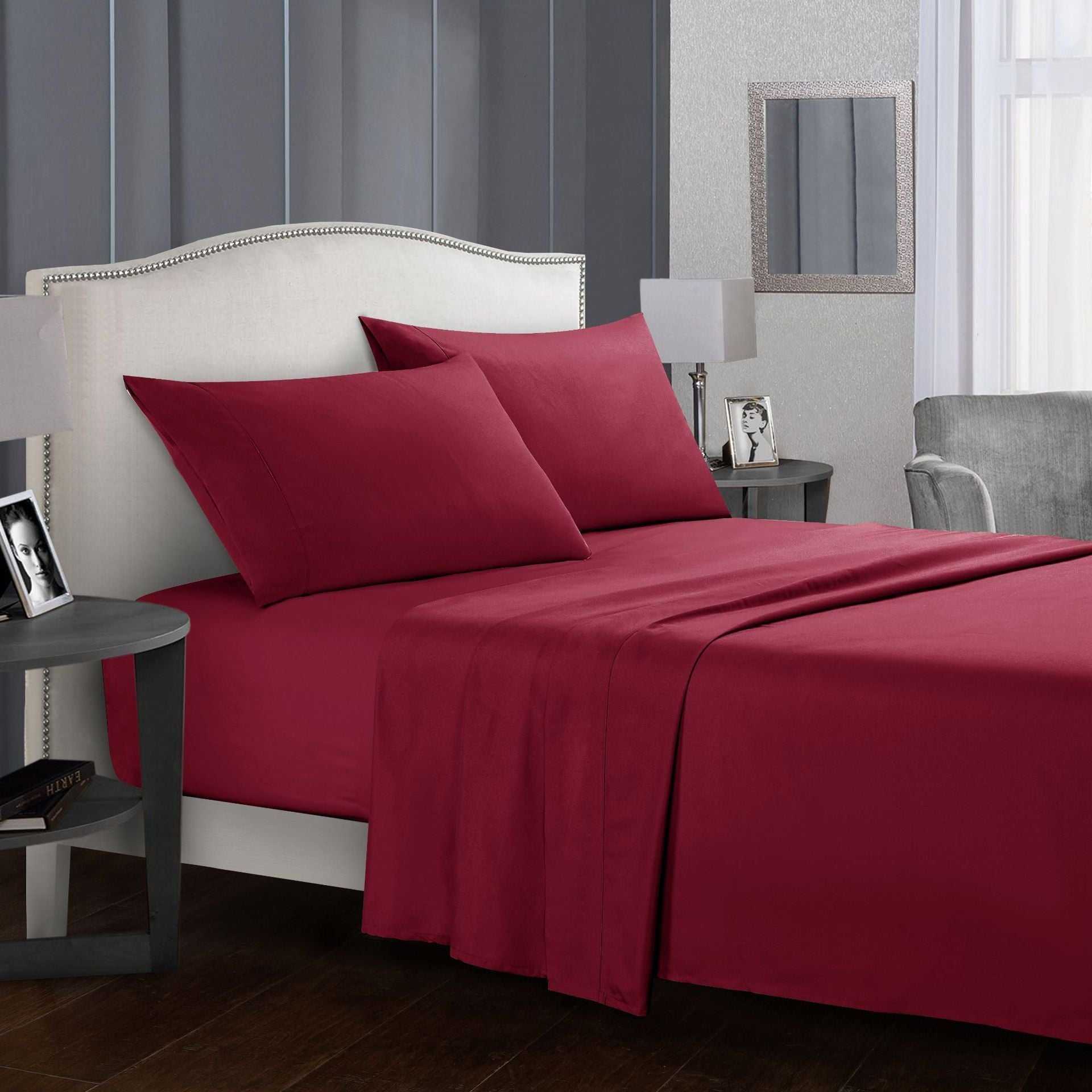 Four-piece bed sheet set in rich red color displayed on a neatly arranged bed.