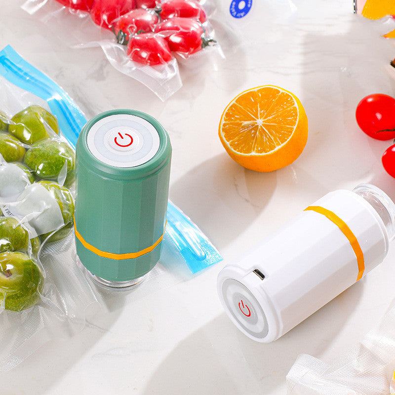 Mini USB charging vacuum sealer in emerald green and milky white with vacuum-sealed food bags on a kitchen counter.