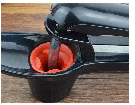 Cherry Red Date cherry kernel remover tool with black and red design on wooden surface.