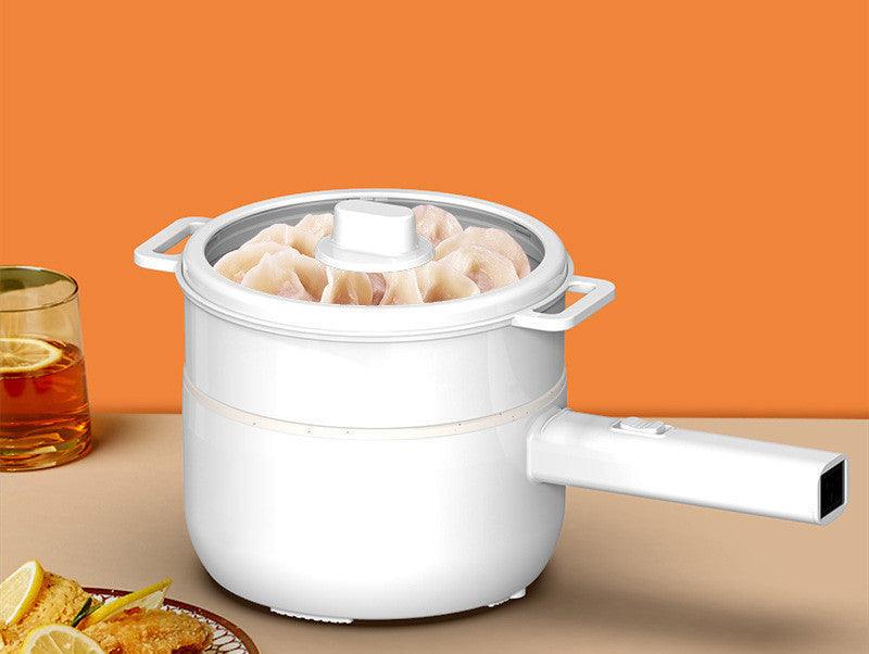 Multifunctional electric cooker with glass lid, cooking dumplings on a table with orange background.