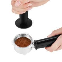 Close-up of a tamper pressing coffee grounds into a portafilter for the Geek Chef Espresso Machine.