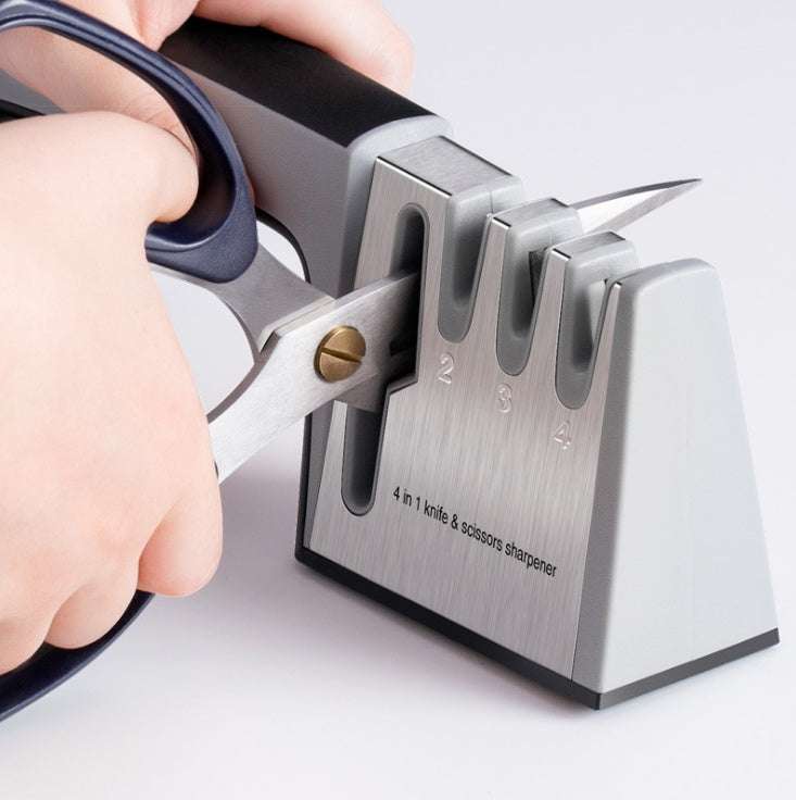 Fast knife sharpener in use with scissors, made from stainless steel and ABS plastic.