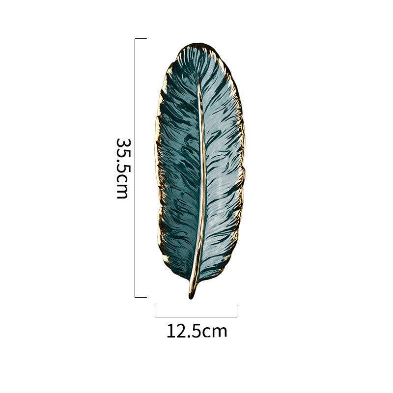 Green ceramic leaf storage tray with golden accents and smooth glaze finish.