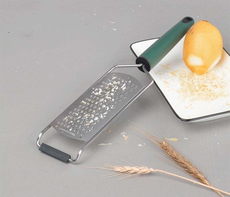 Kitchen gadgets stainless steel cheese grater with lemon zest on a plate.